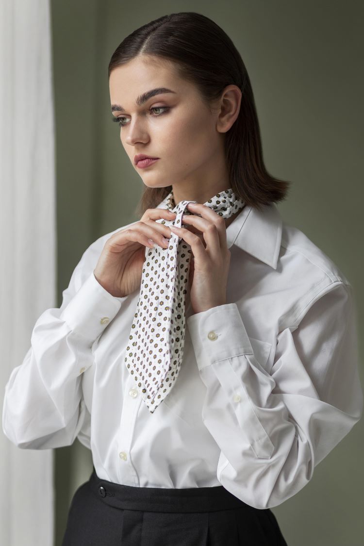 Lady in white shirt ties a white polka dotted scarf