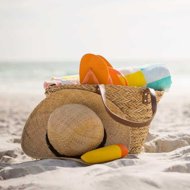 A well stocked woven beach back holds towel, flip flops, suncream and a crushable straw hat