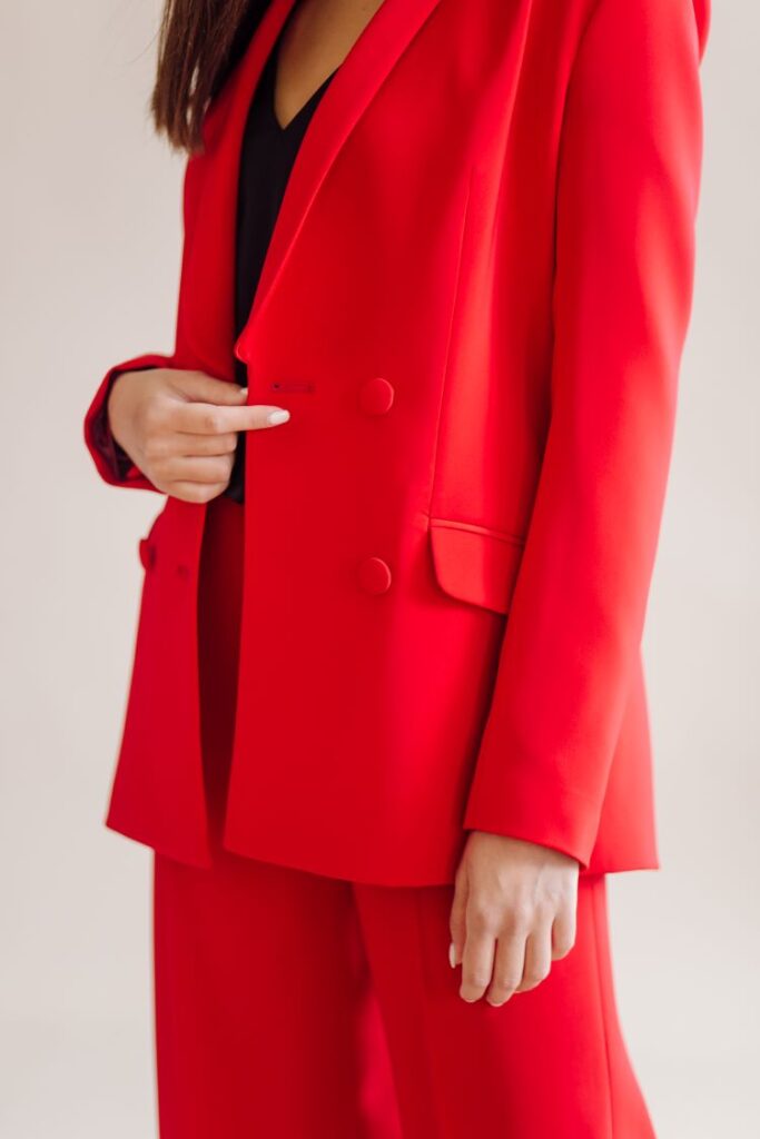 Closeup of a woman in a loose fitting bold red suit with a black top underneath.