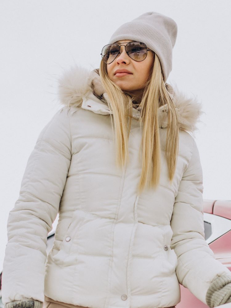 Keeping warm in a thick white padded jacket with fake fur trim around the hood, and a warm knitted beanie.