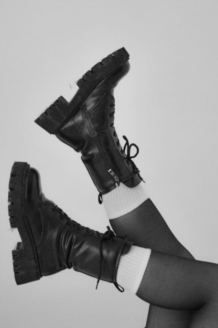 Pair of legs waving in the air wearing  black boot with white socks and black tights